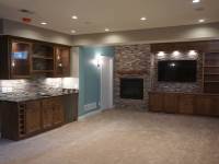 A custom designed, built and installed basement with a birch wet bar and bookcases by Cabinet Innovations.